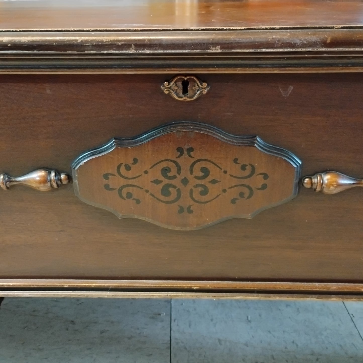 Close-up of vintage Lane cedar chest showing decorative front panel, keyhole, wood trim, and age-related wear.