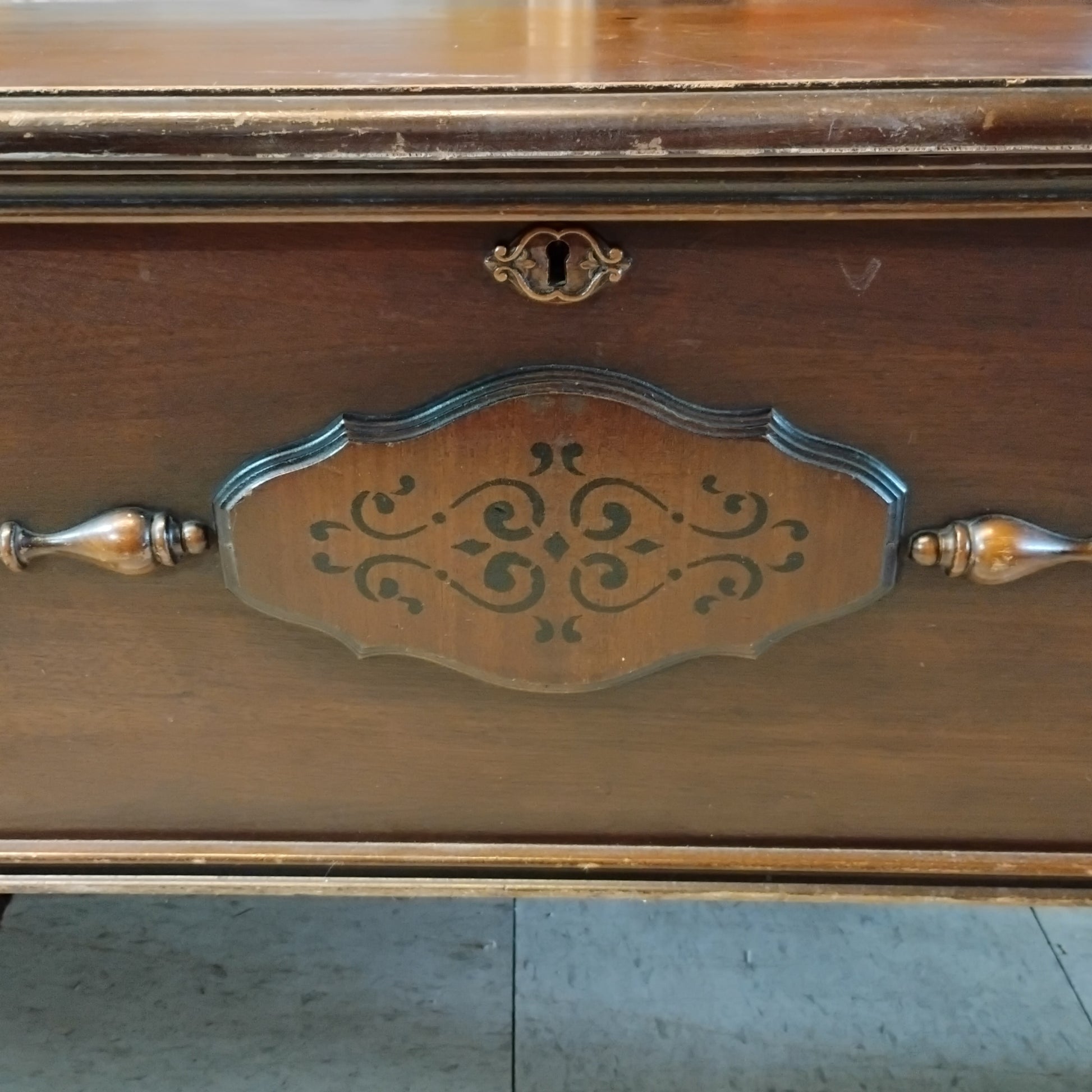 Close-up of vintage Lane cedar chest showing decorative front panel, keyhole, wood trim, and age-related wear.