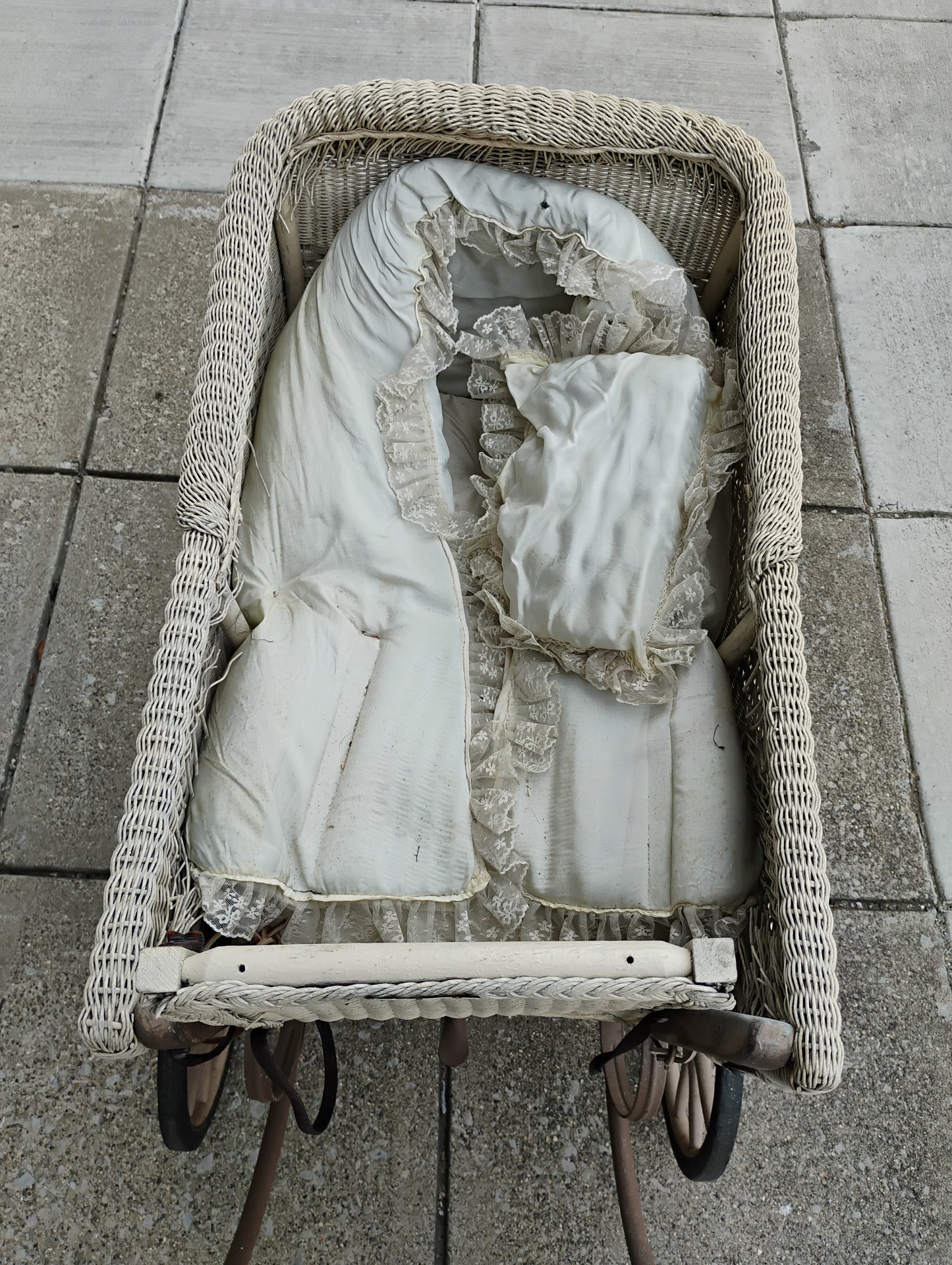 Antique baby carriage with lace bedding on a sidewalk