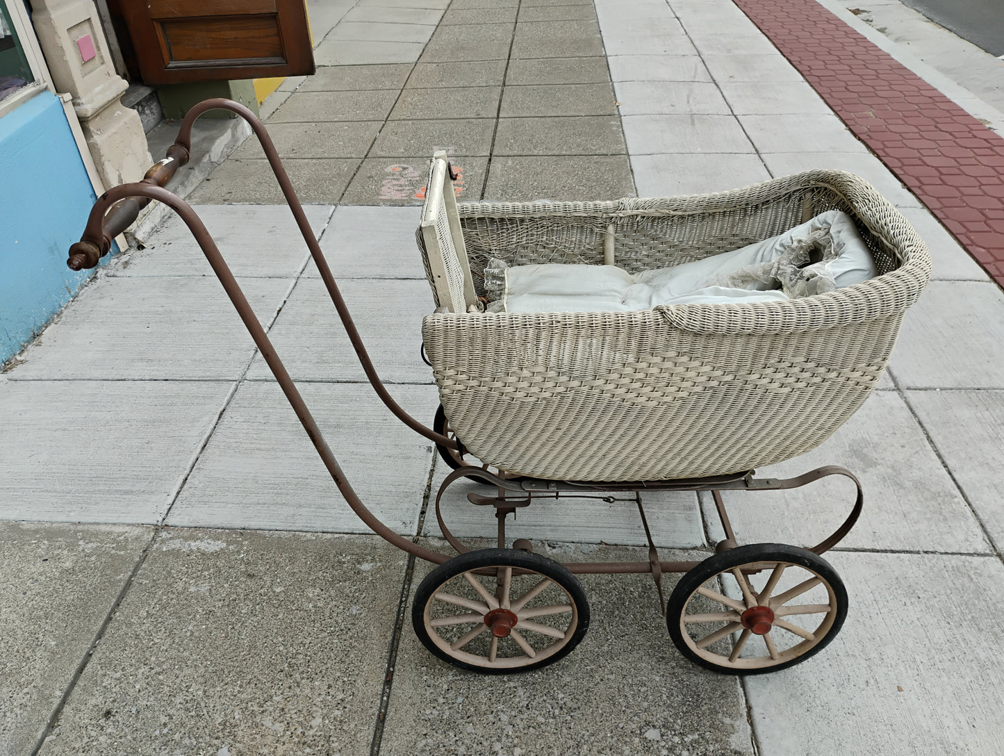 Antique Heywood-Wakefield wicker baby carriage with spoked wheels and curved iron undercarriage, circa 1910s
