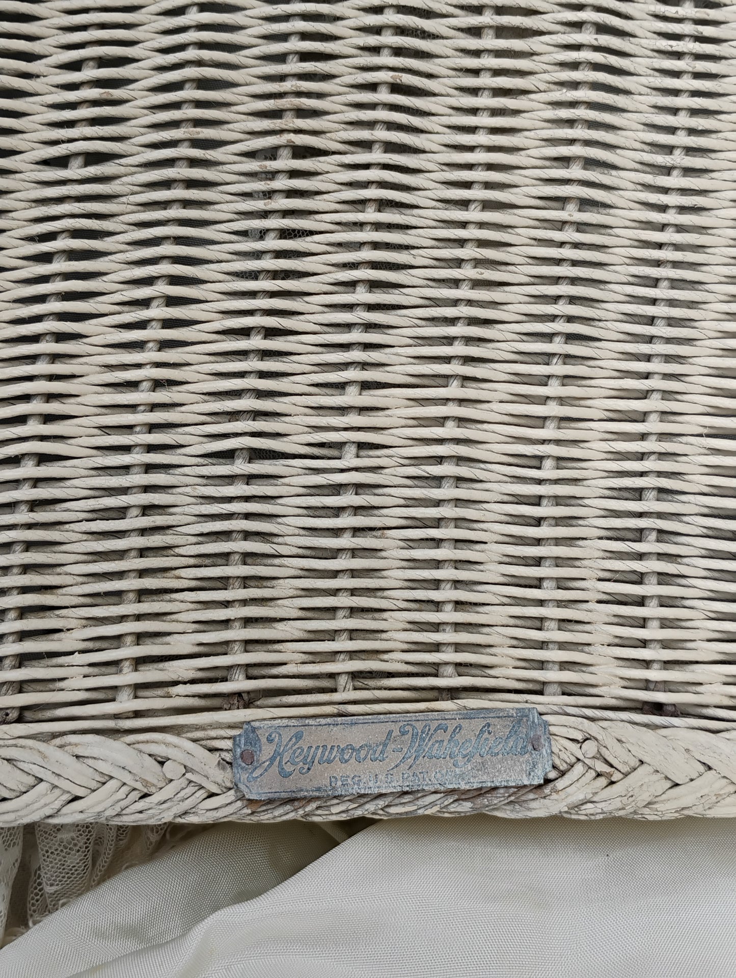 Front view of an antique Heywood-Wakefield wicker baby carriage showing the hinged drop door and ‘Pat. Pending’ label.