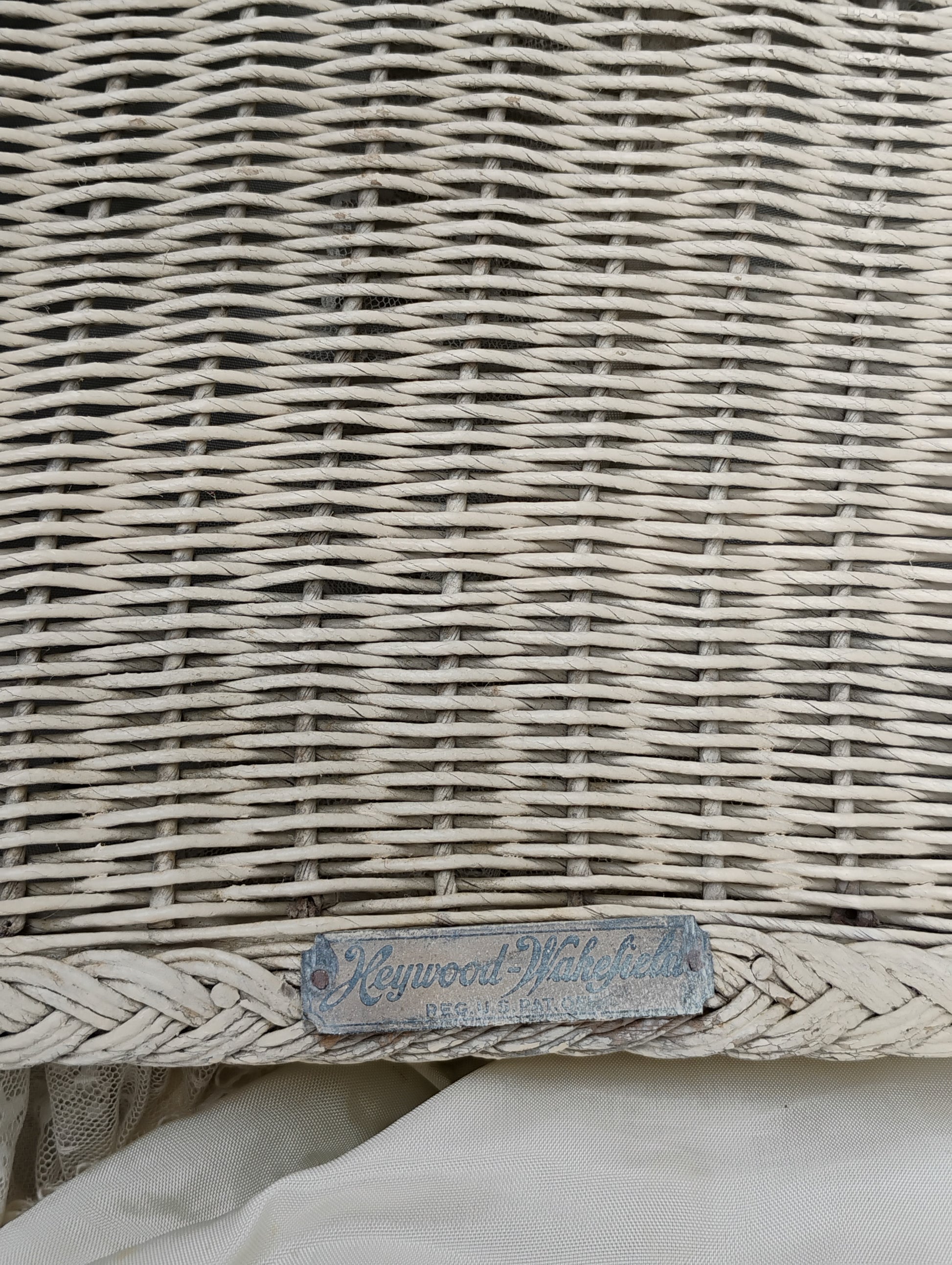 Front view of an antique Heywood-Wakefield wicker baby carriage showing the hinged drop door and ‘Pat. Pending’ label.