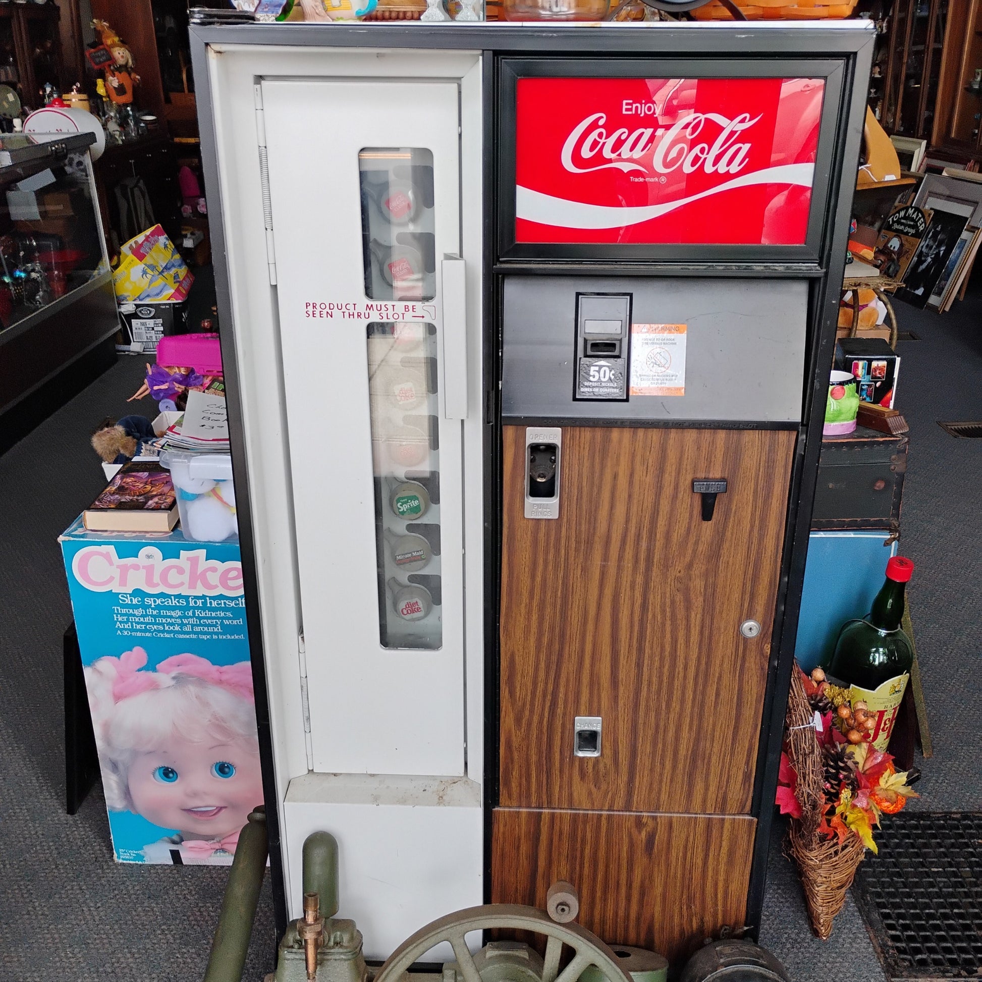 Vintage Coca-Cola vending machine in a store setting with various items around